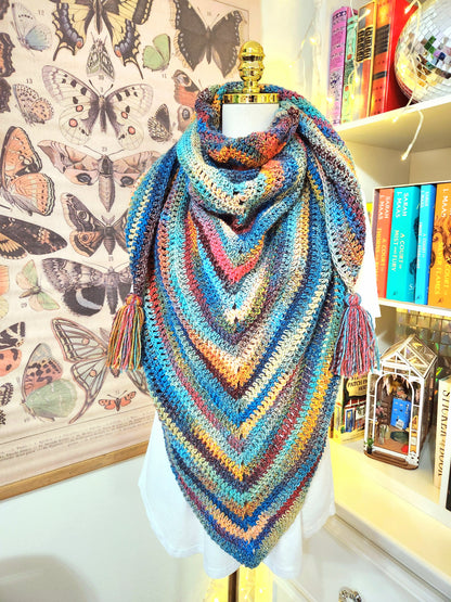 Colorful crocheted shawl on a mannequin with butterfly illustrations in the background