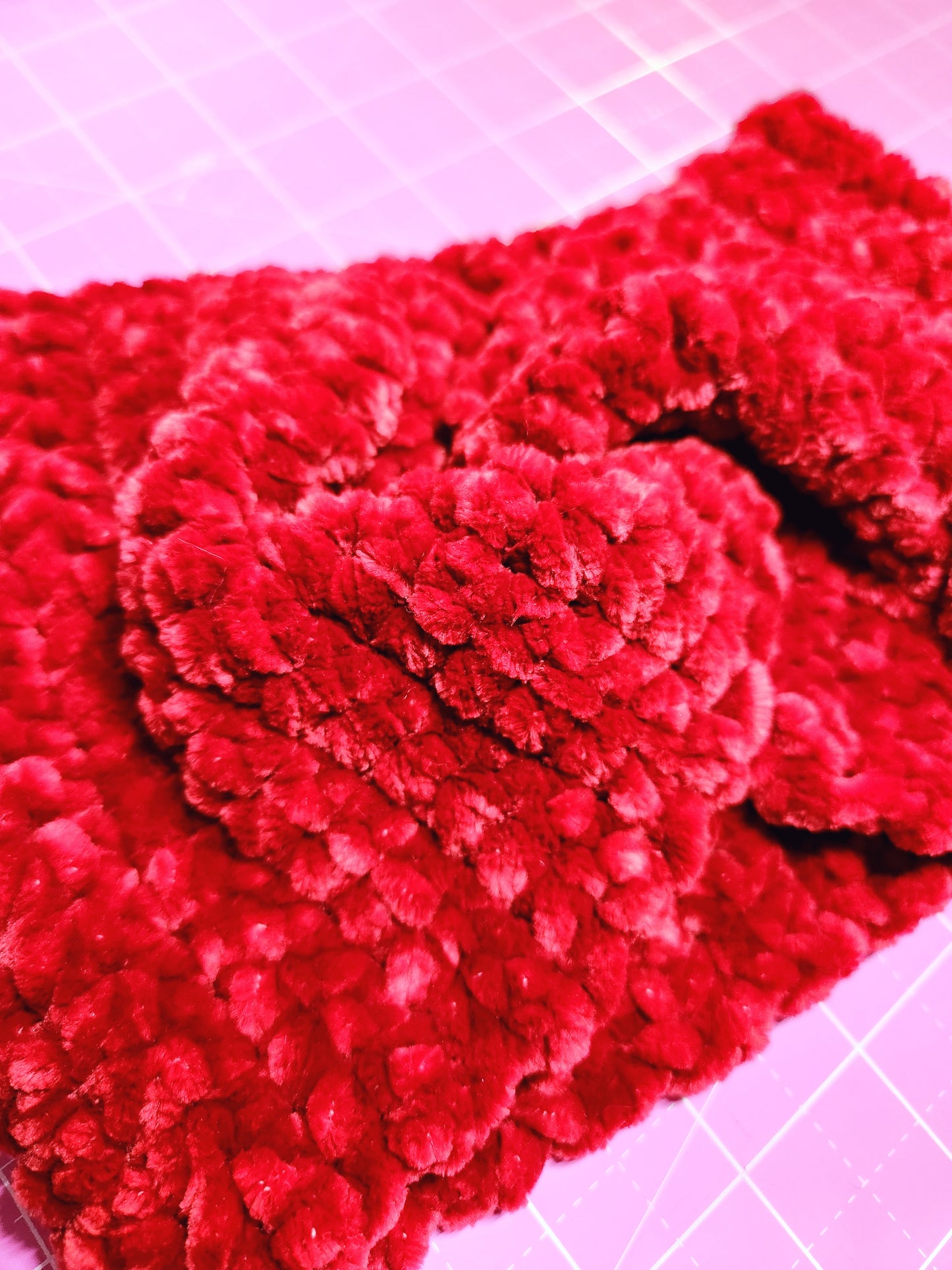 Close-up of a red textured fabric on a pink grid background
