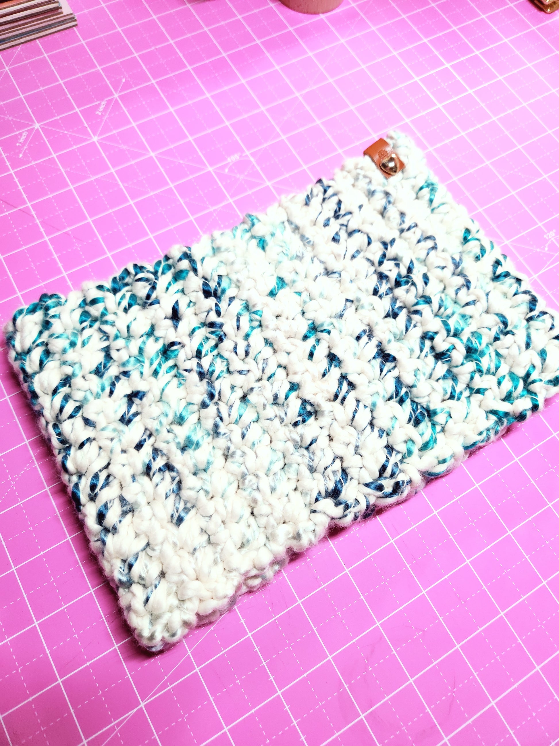 Crocheted fabric with a white and blue pattern on a pink cutting mat