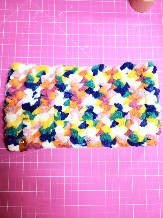 Colorful crocheted phone case on a pink grid background