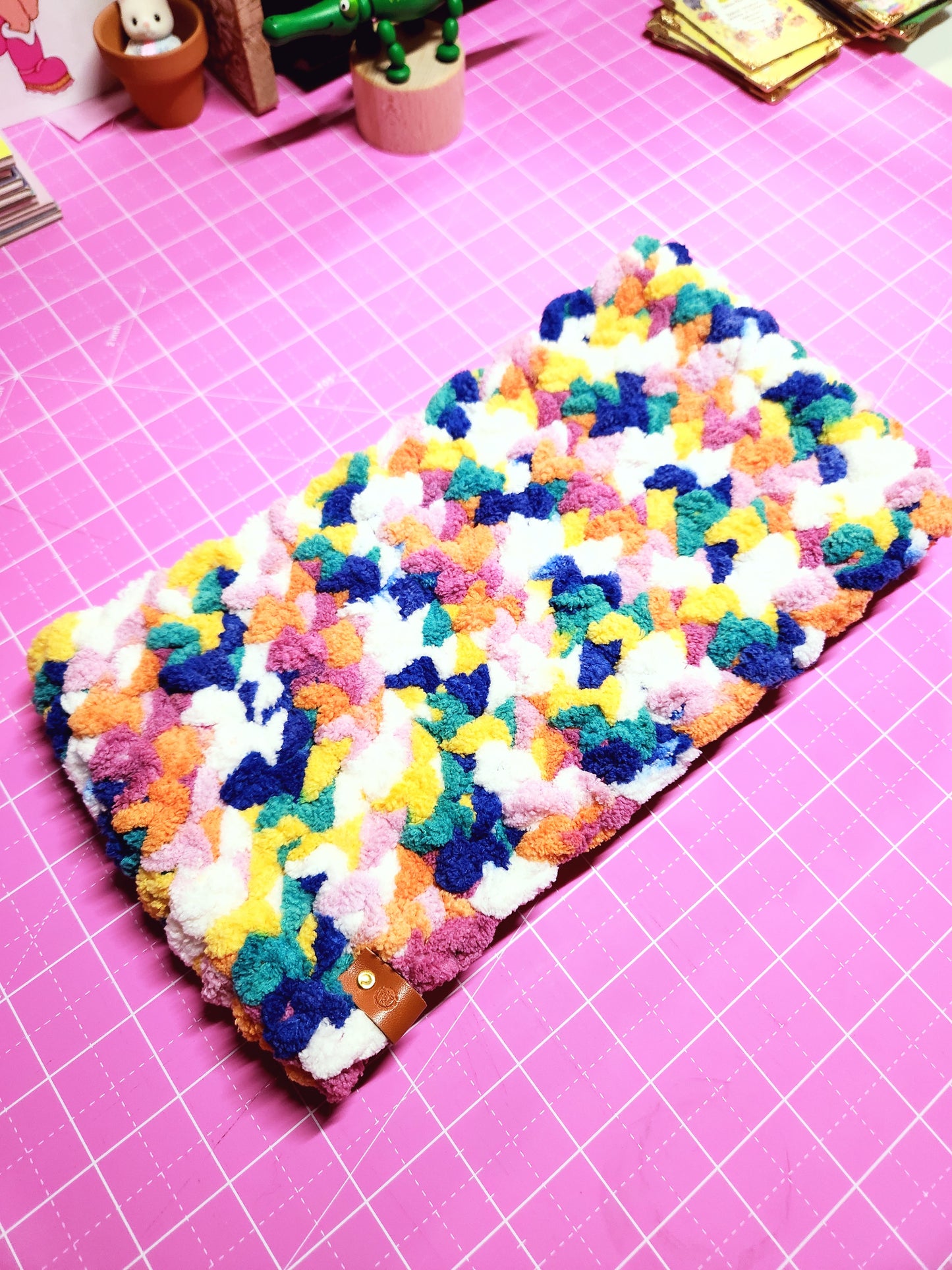 Colorful textured phone case on a pink cutting mat with tools.