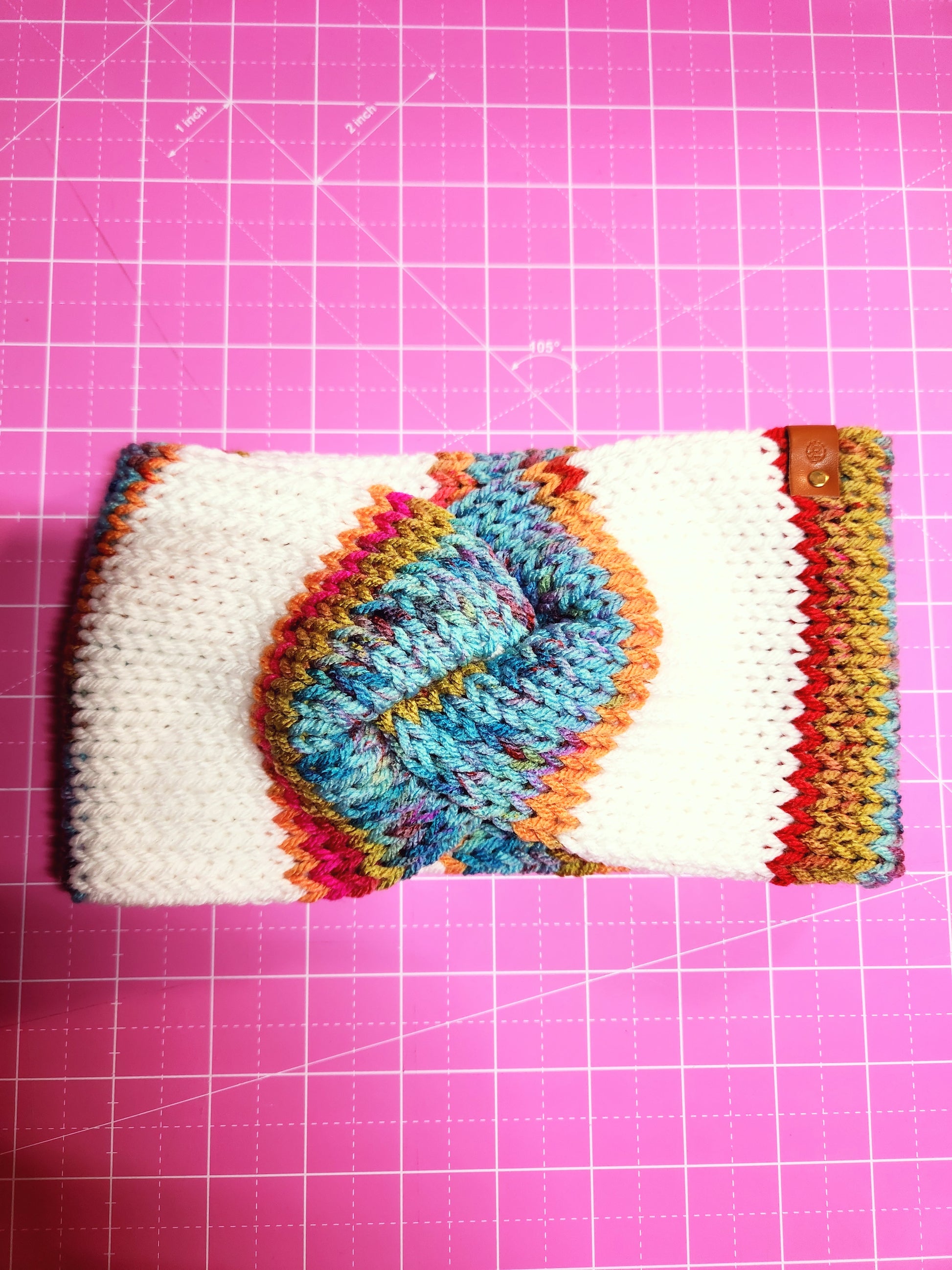 Colorful knitted phone case on a pink grid background