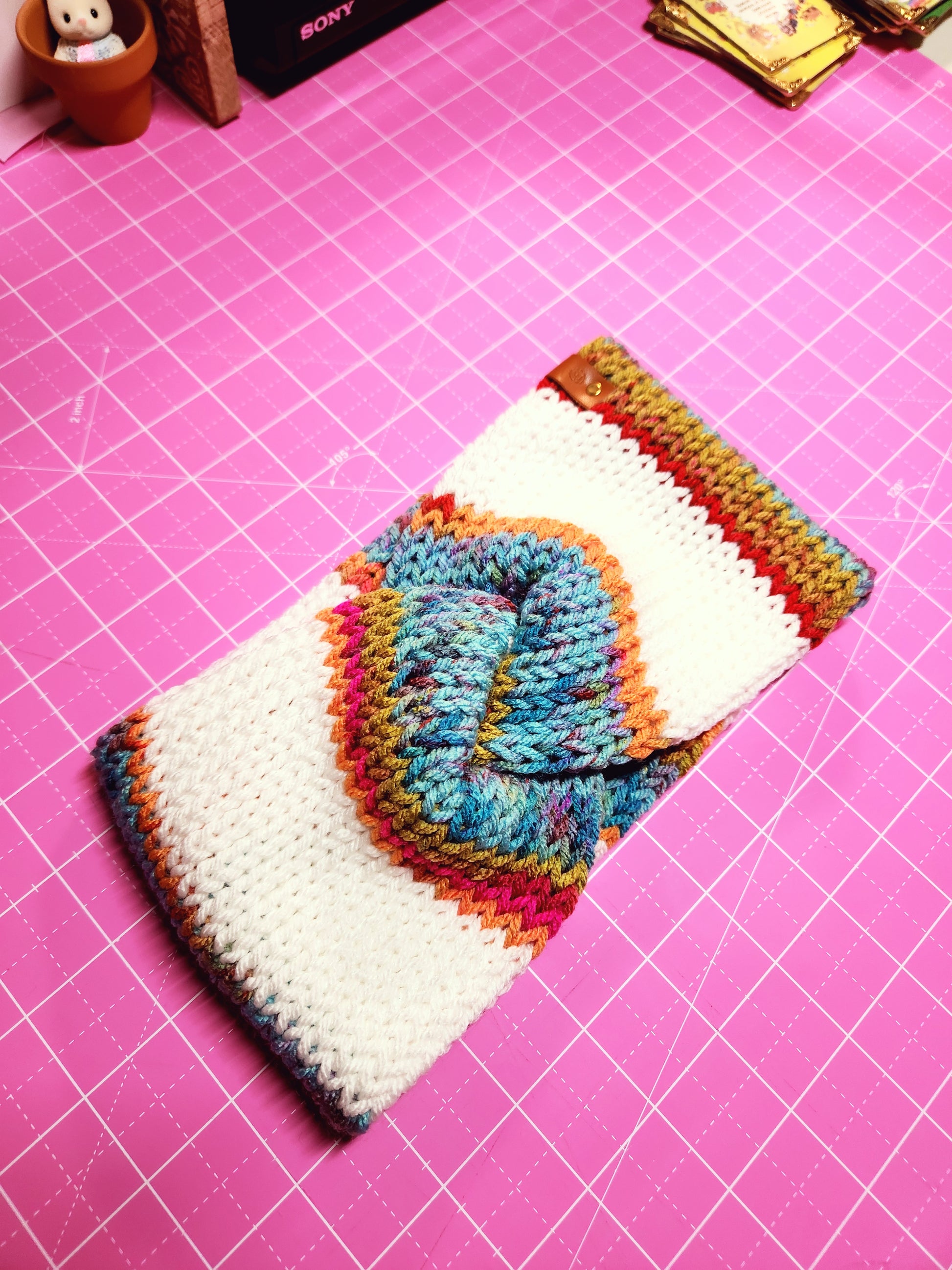 Colorful knitted pouch on a pink cutting mat