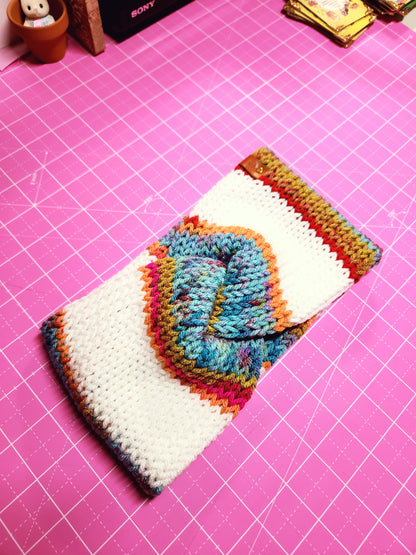 Colorful knitted pouch on a pink cutting mat