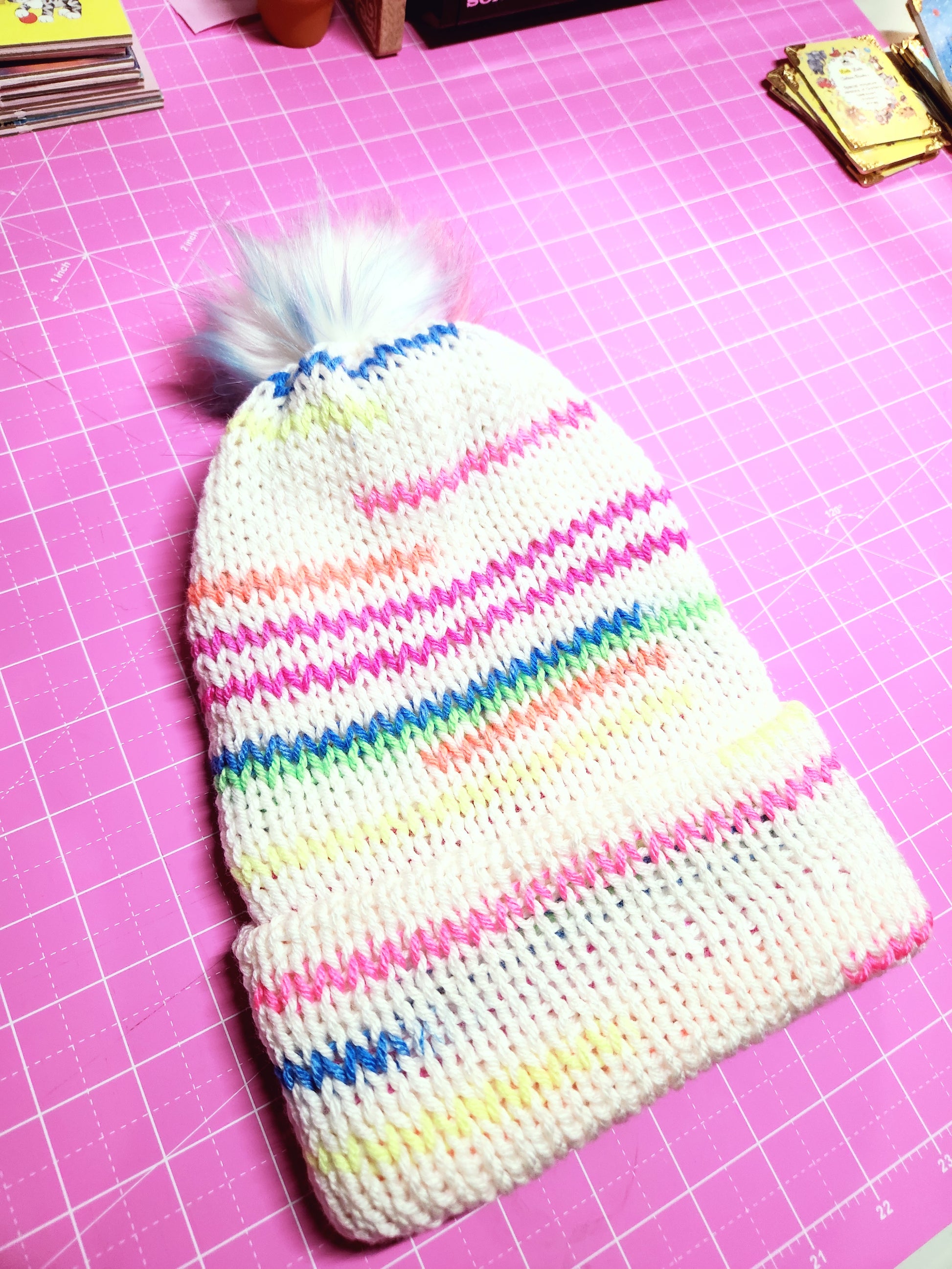 Knitted pouch with colorful stripes on a pink grid background