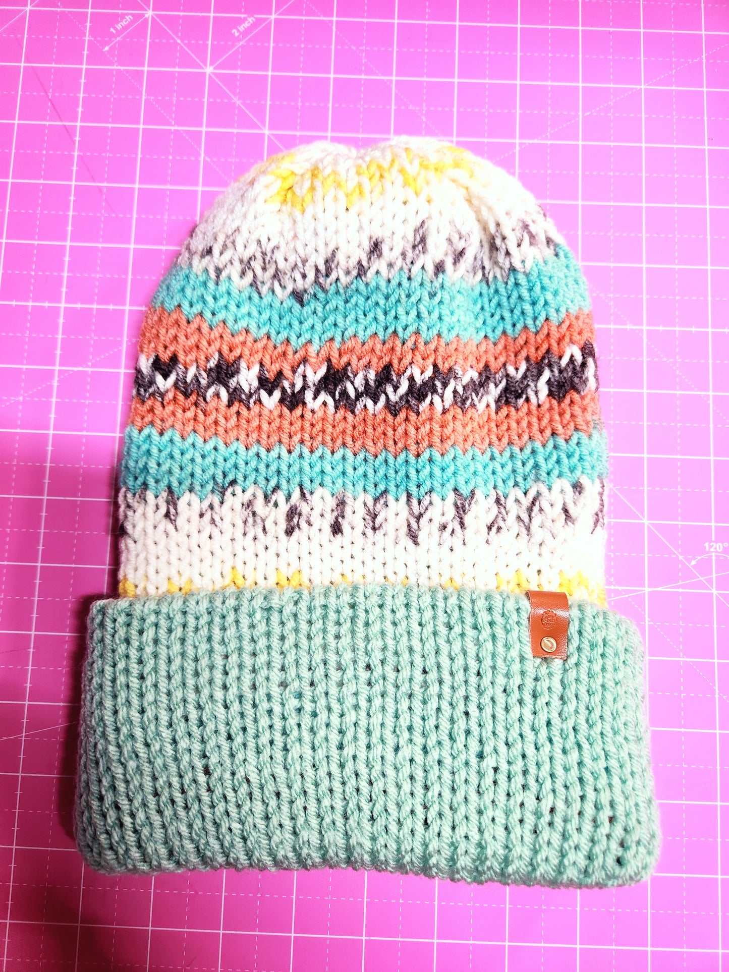 Knitted pouch with colorful stripes on a pink grid background