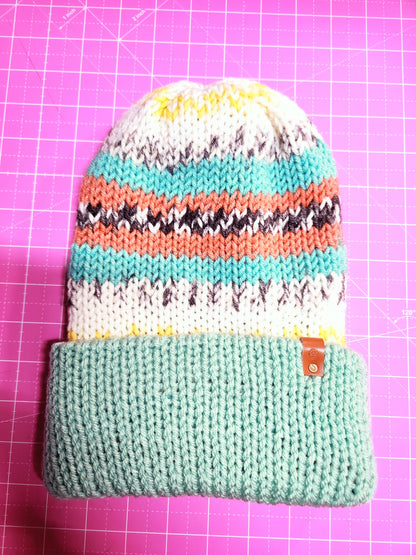 Knitted pouch with colorful stripes on a pink grid background