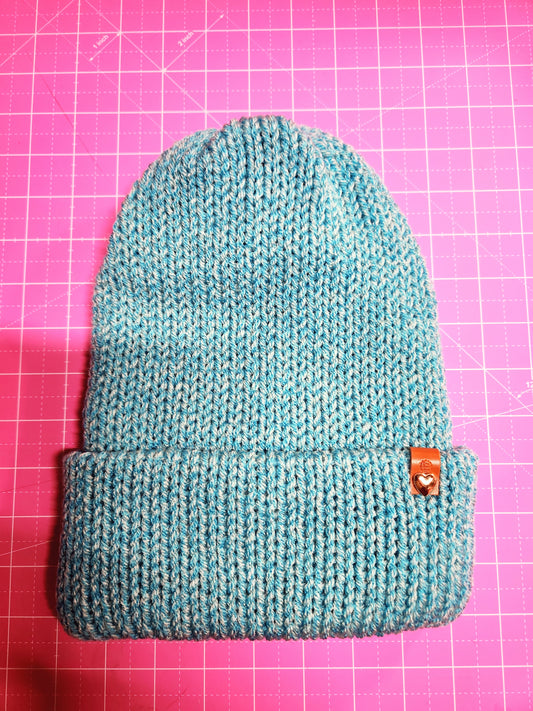 Blue knitted pouch with a button on a pink grid background