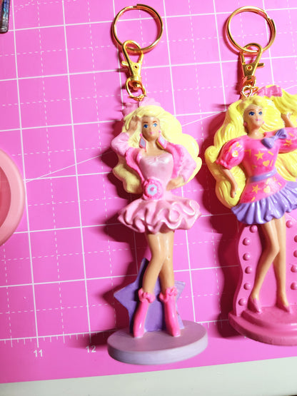 Barbie-themed keychains on a pink cutting mat