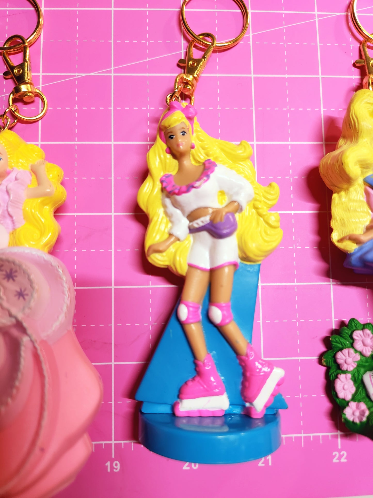 Barbie figurine with blonde hair and white dress on a pink grid background