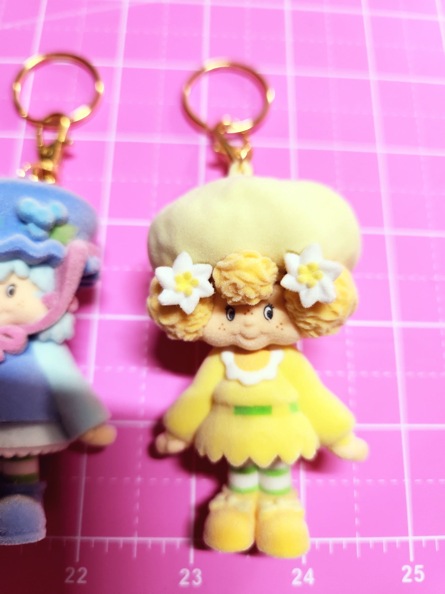 Toy figure of a character with yellow dress and flowers on a pink grid background