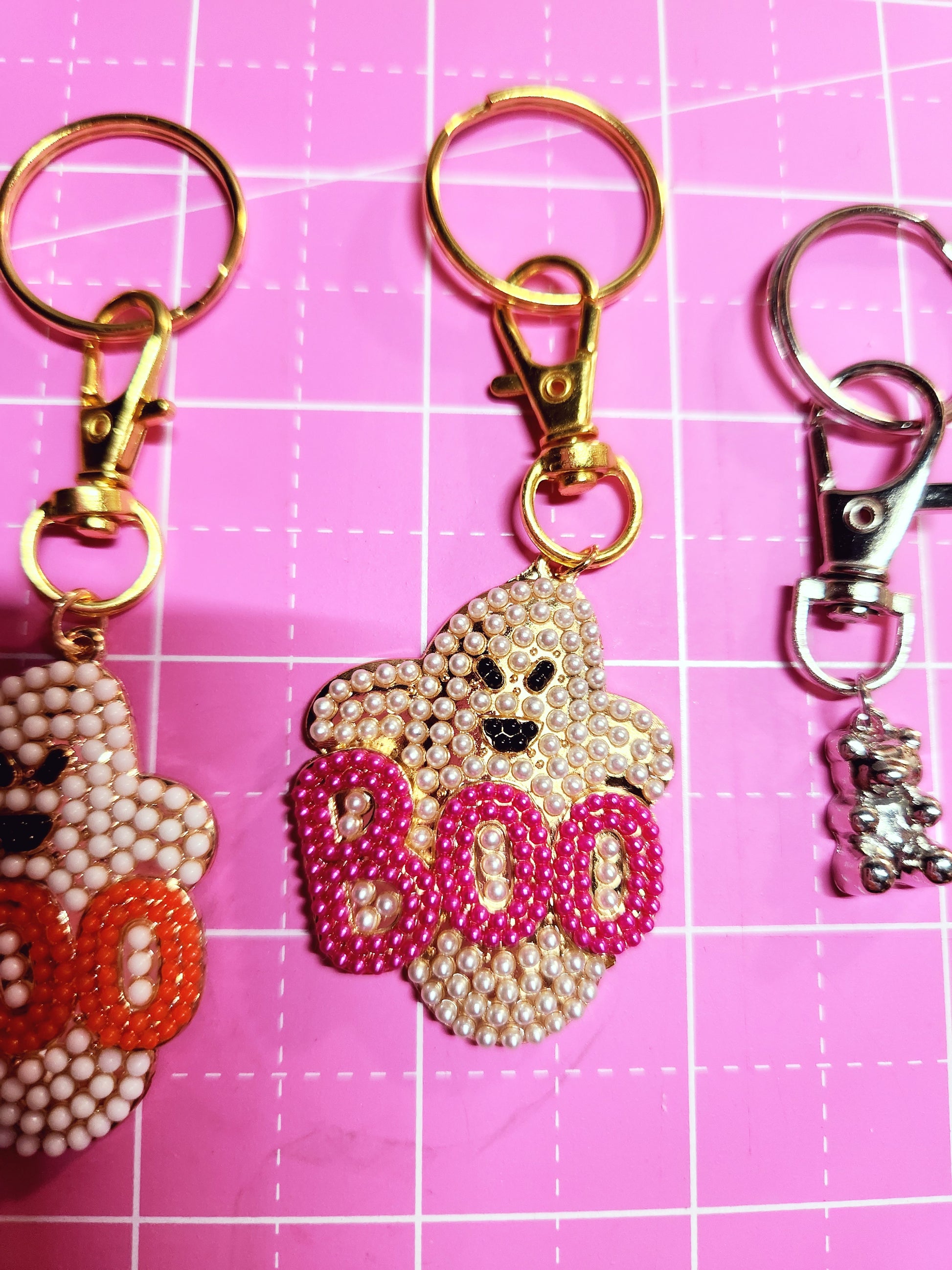 Decorative keychains with star and heart designs on a pink grid background