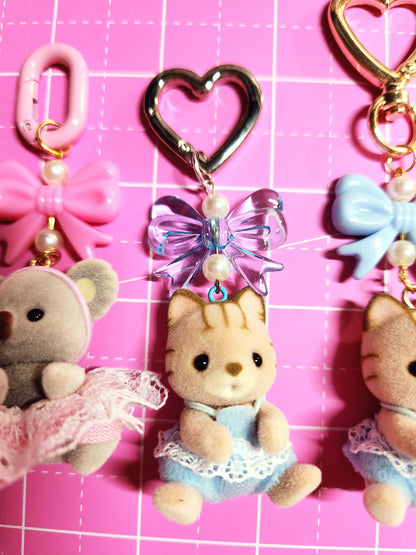 Collection of decorative keychains and charms on a pink grid background