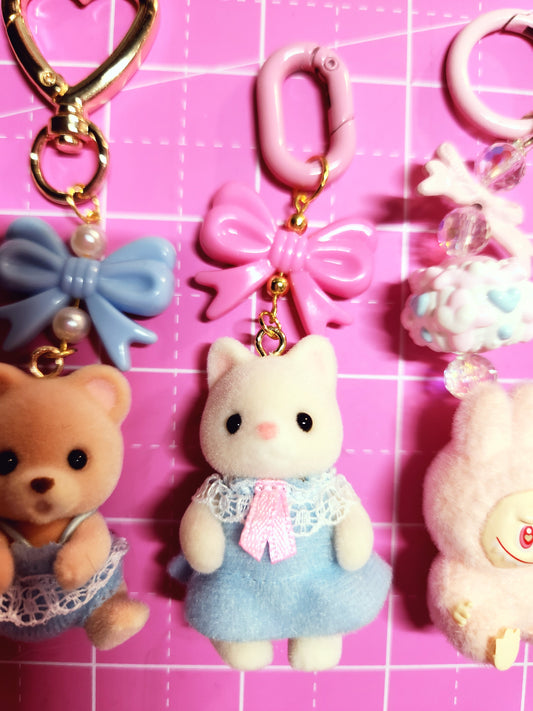 Collection of colorful keychains and plush toys on a pink grid background