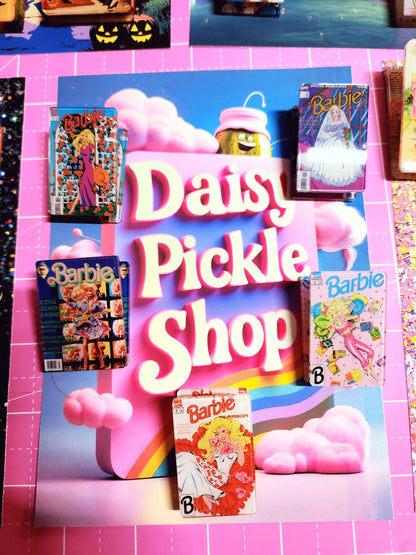 Toy store display with 'Daisy Pickle Shop' and Barbie toys on a colorful surface.