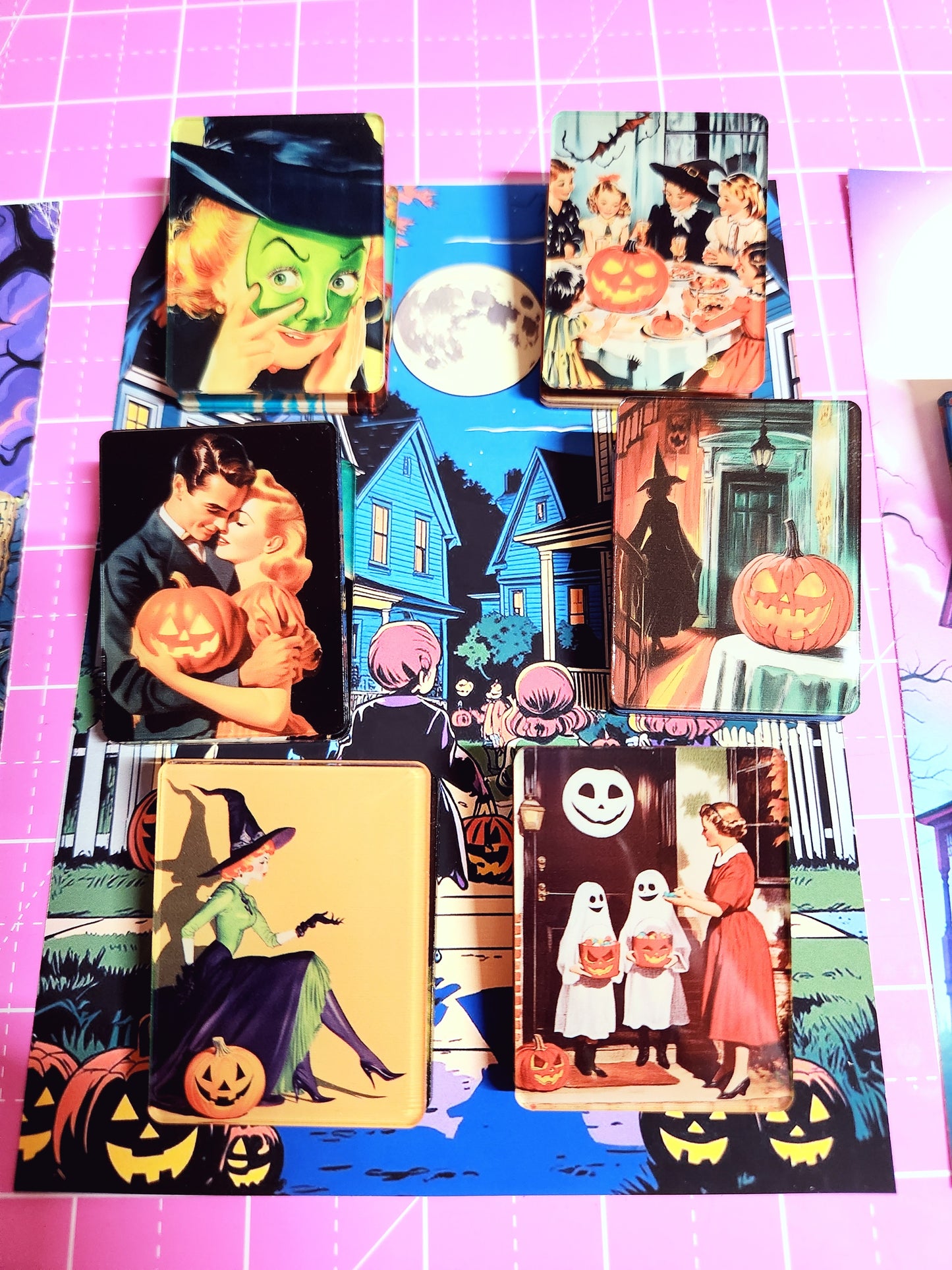 Collection of Halloween-themed trading cards on a pink grid background