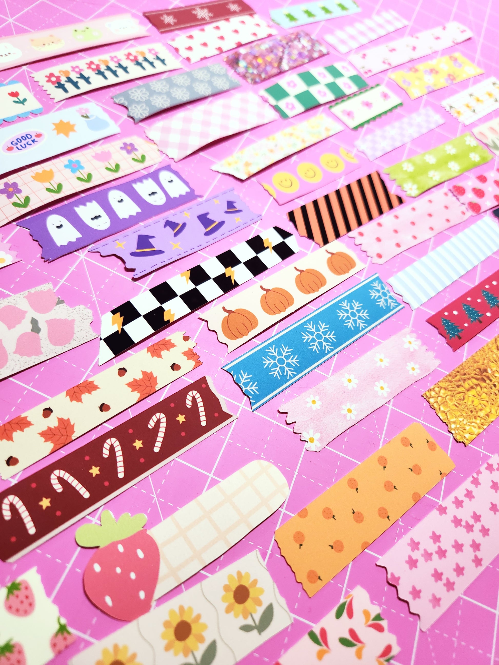 Collection of colorful washi tape rolls on a pink background