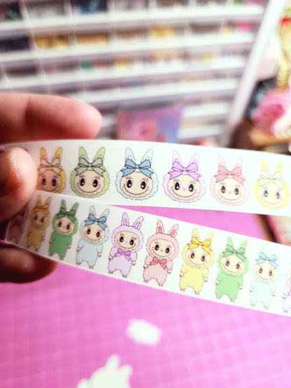 Strip of cartoon character stickers held by a hand with a blurred background