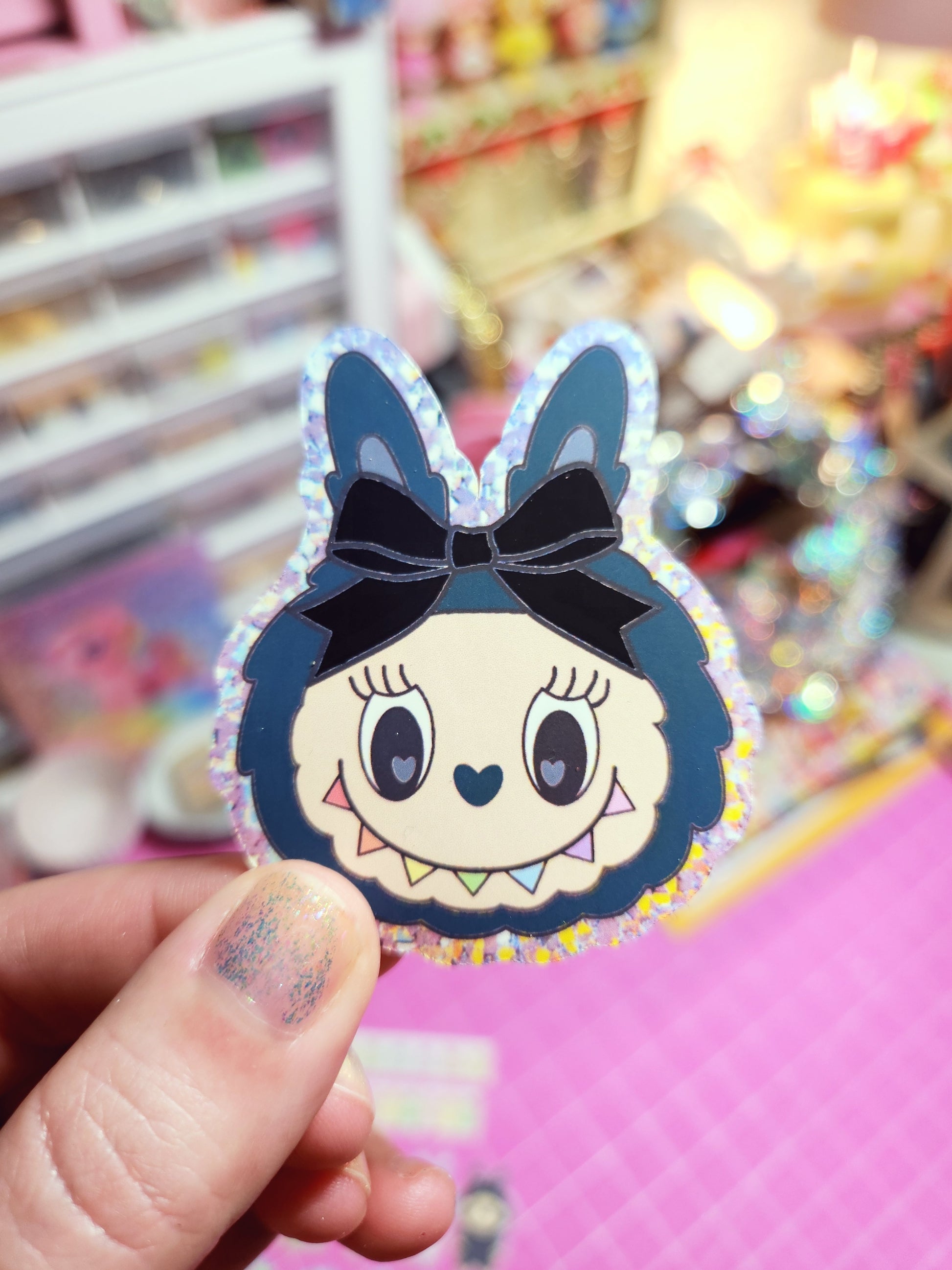 Cartoon character sticker with a bow held by a hand against a colorful background