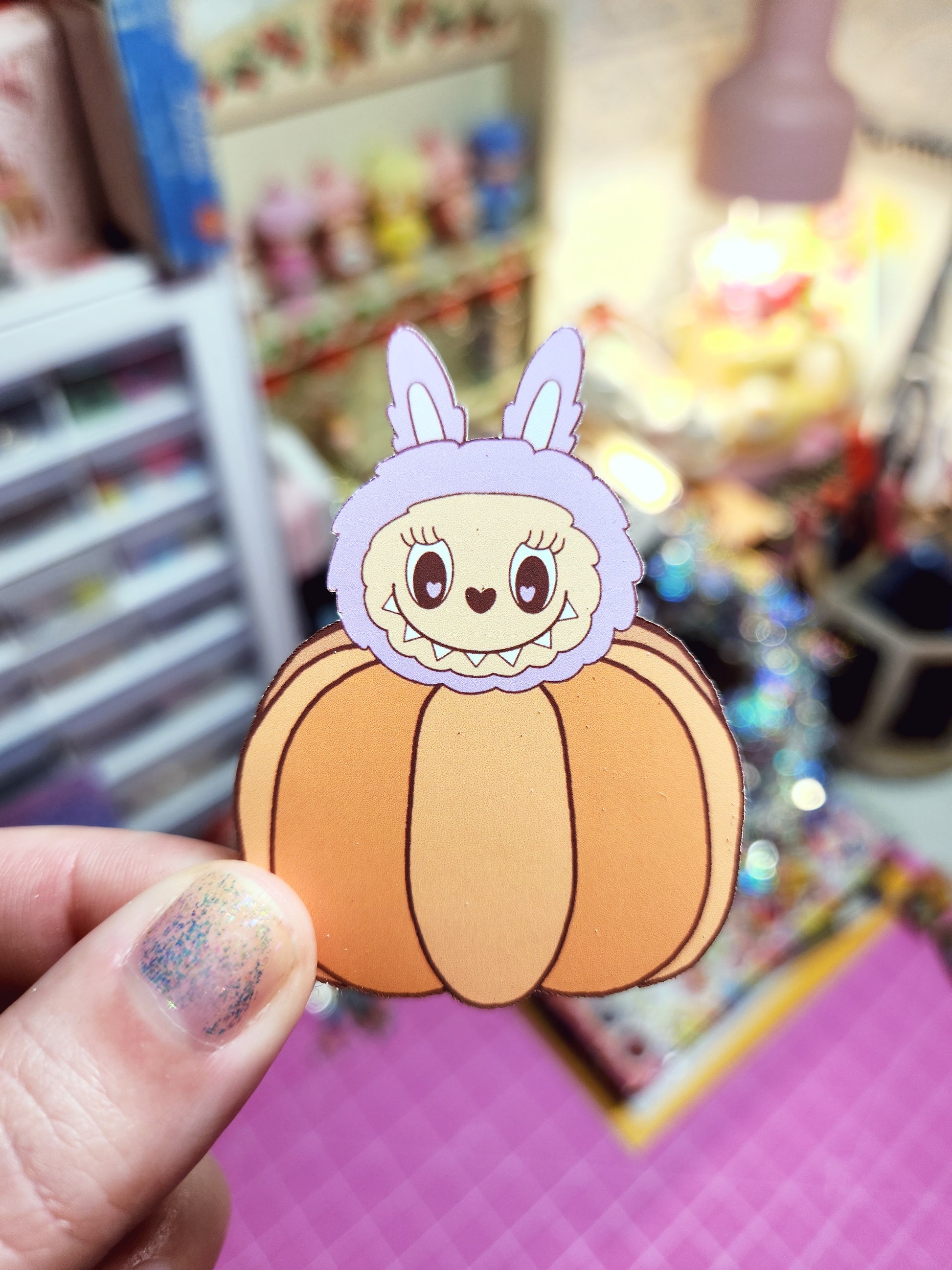 Cartoon character sticker on a pumpkin held by a hand with colorful background