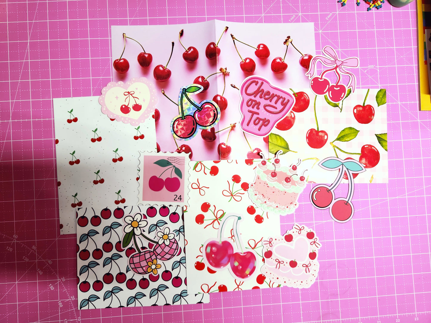 Collection of cherry-themed stationery items on a pink grid background
