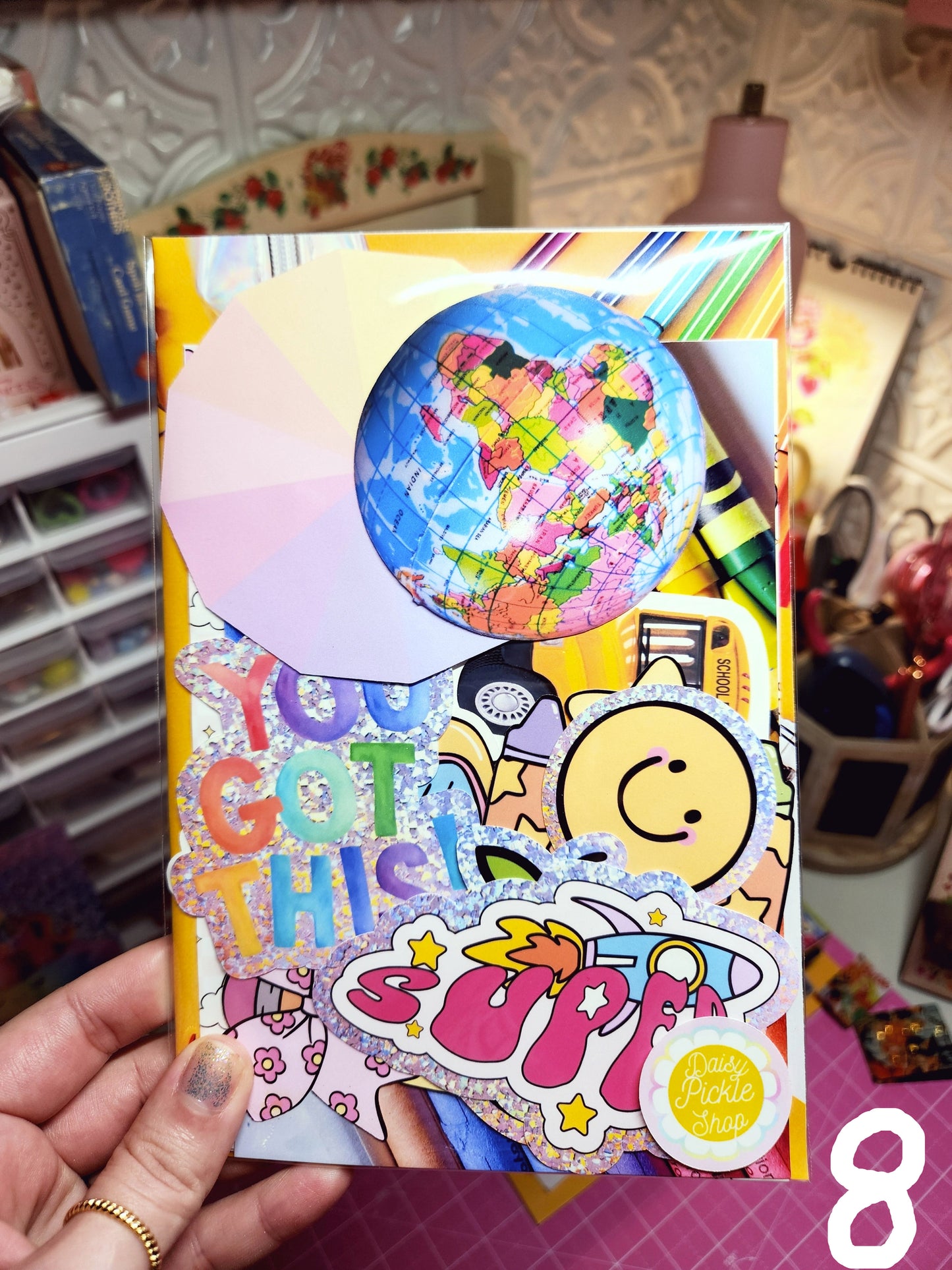 Colorful card with text and graphics held by a hand in a casual setting