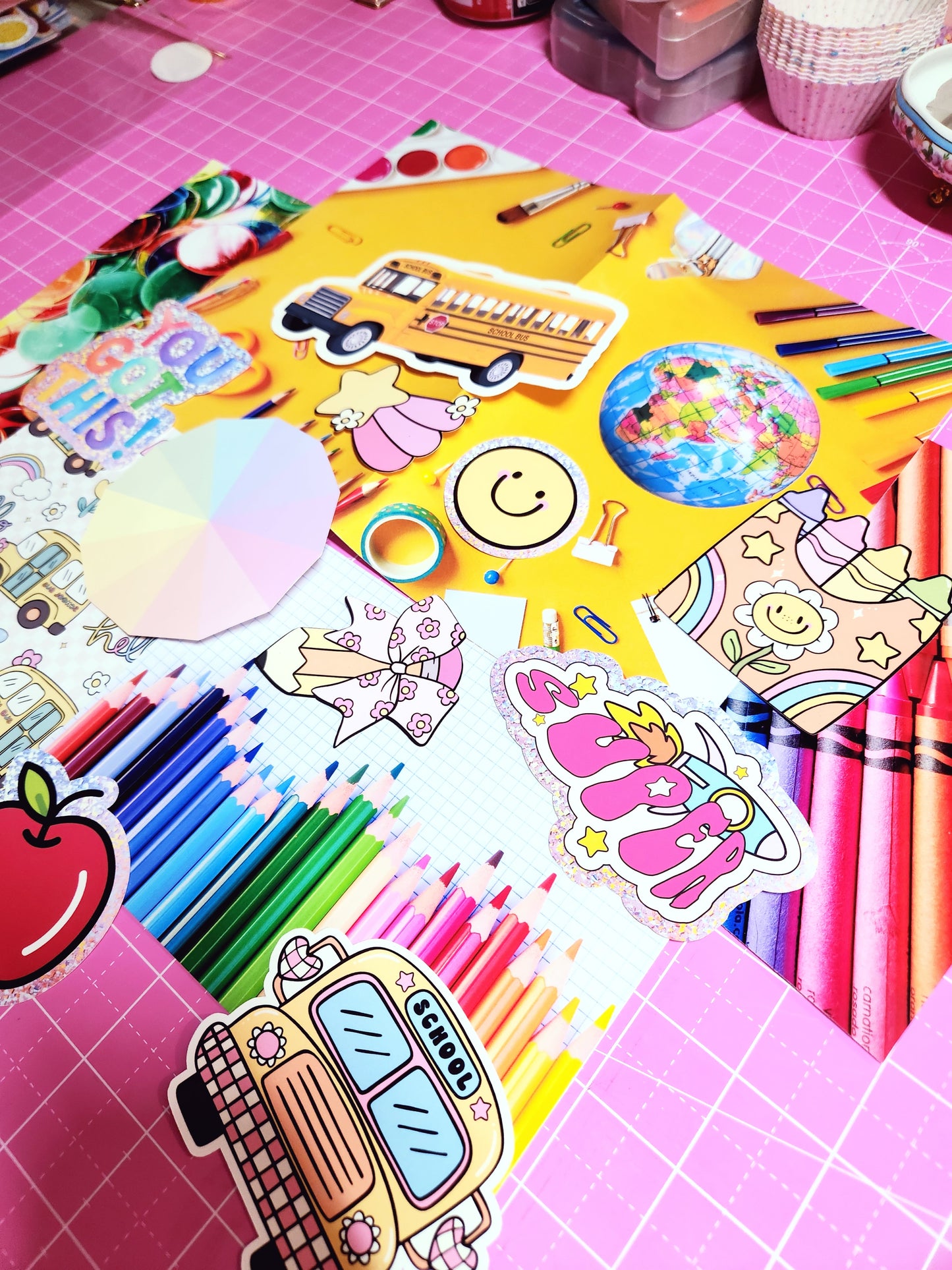 Colorful stationery items including stickers and markers on a pink grid background