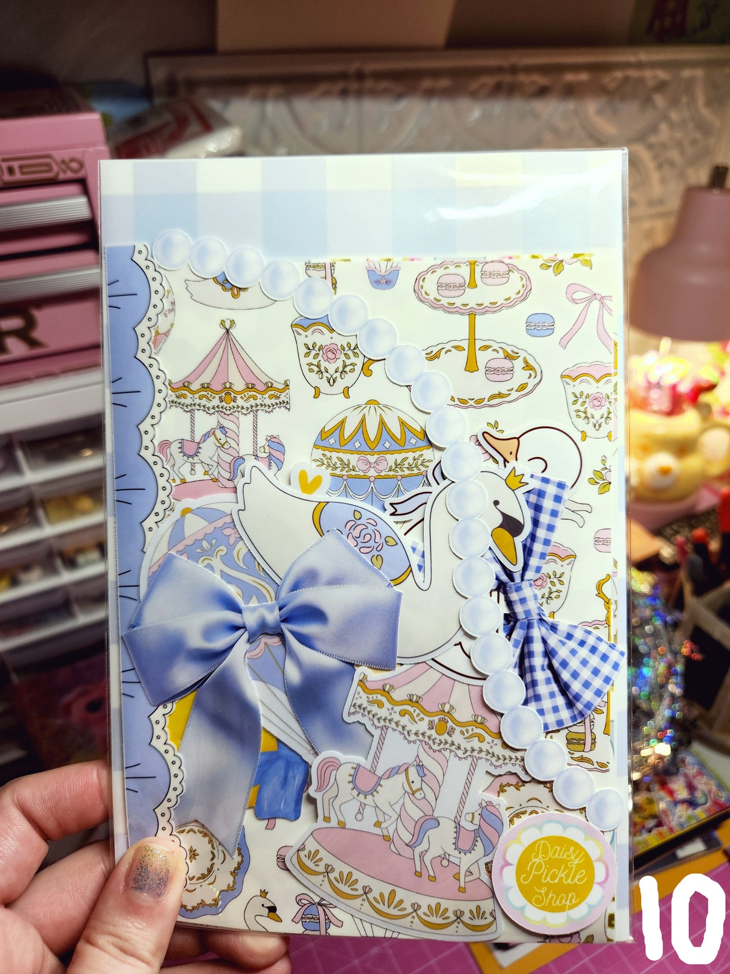 Decorative box with cartoon character and blue bow held by a hand against a colorful background.