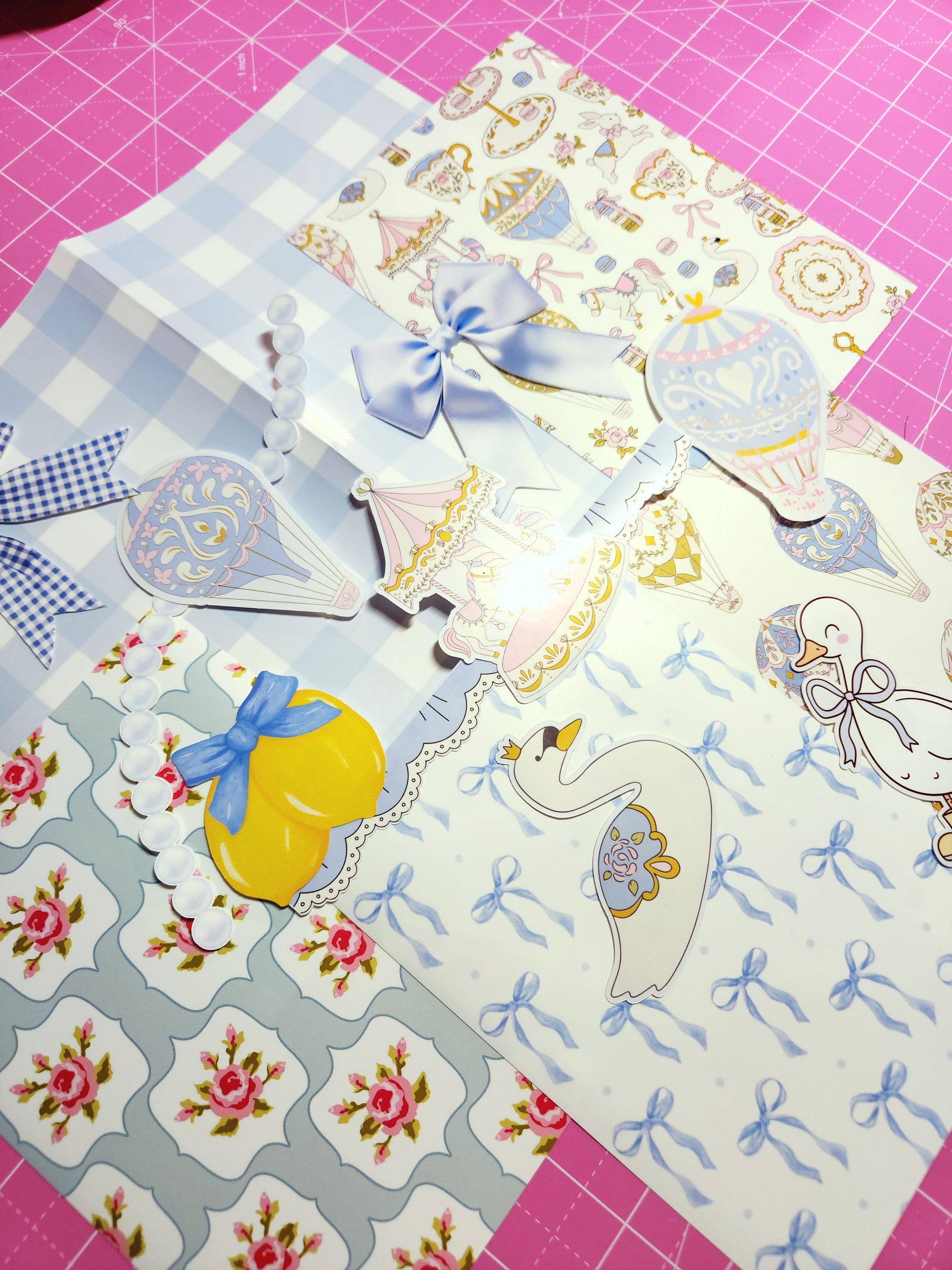 Collection of decorative paper sheets with various patterns on a pink cutting mat.