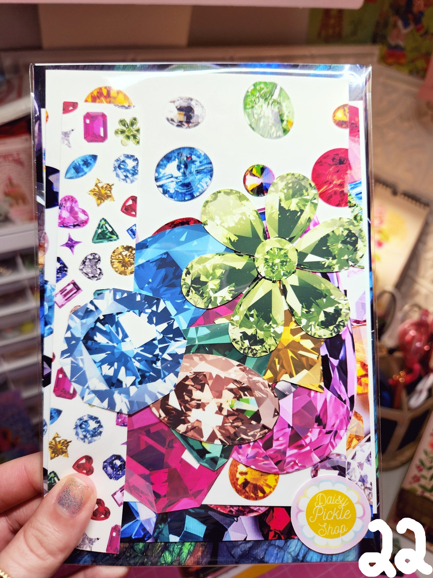 Decorative notebook with colorful gemstone design held by a hand.