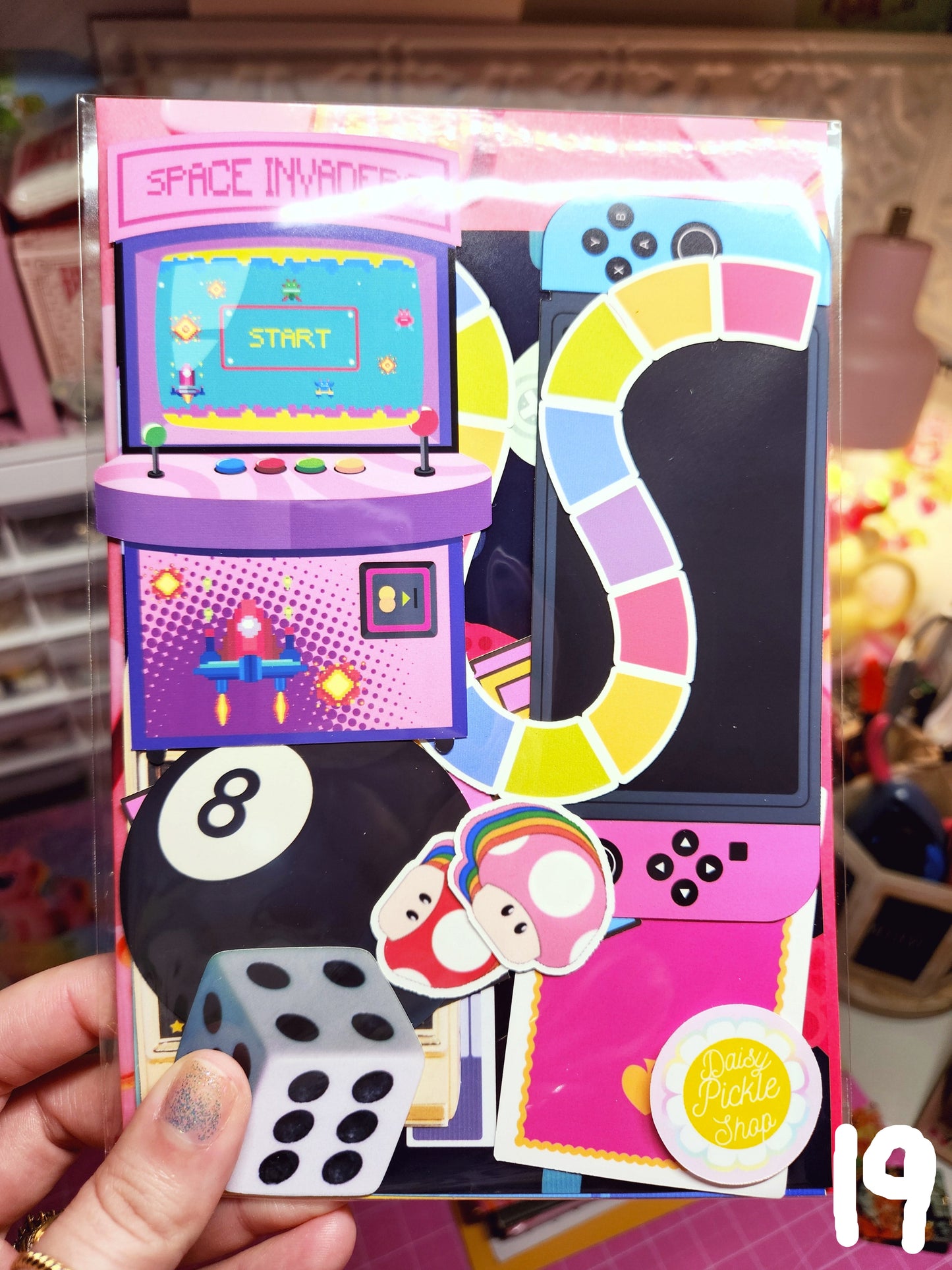 Colorful board game box with gaming elements and a hand holding it.