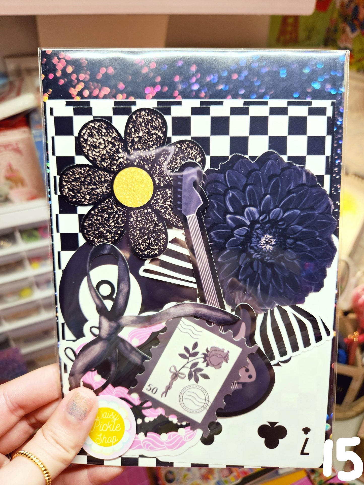 Decorative box with floral designs and checkered pattern held by a hand.