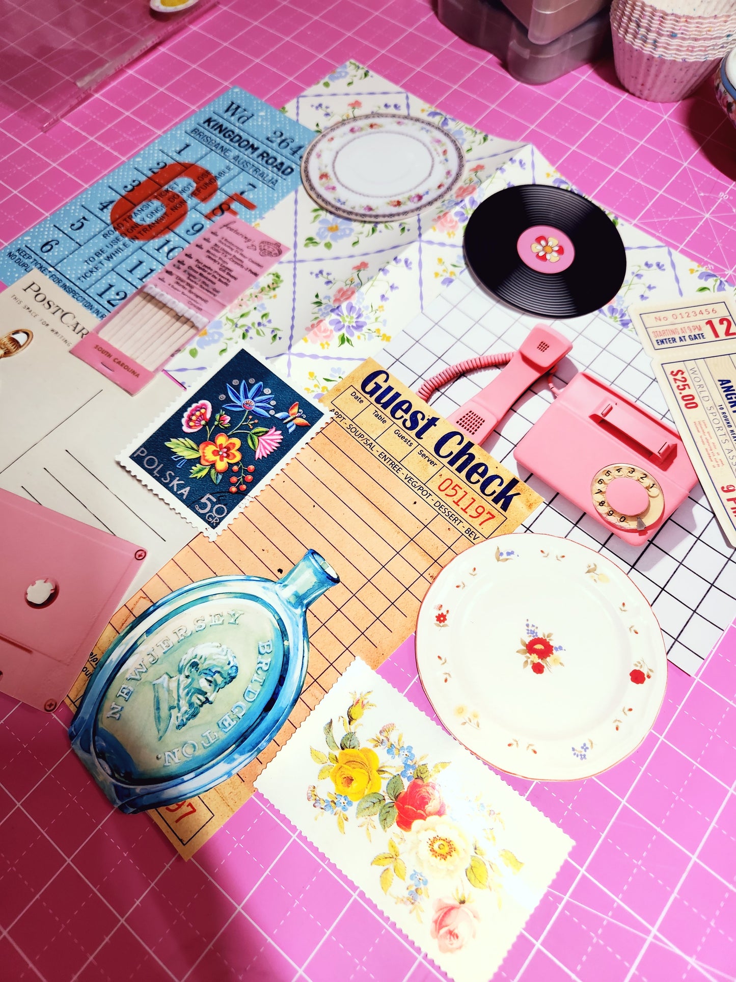 Collection of vintage items including a vinyl record, tickets, and a guest check on a pink surface with grid lines.