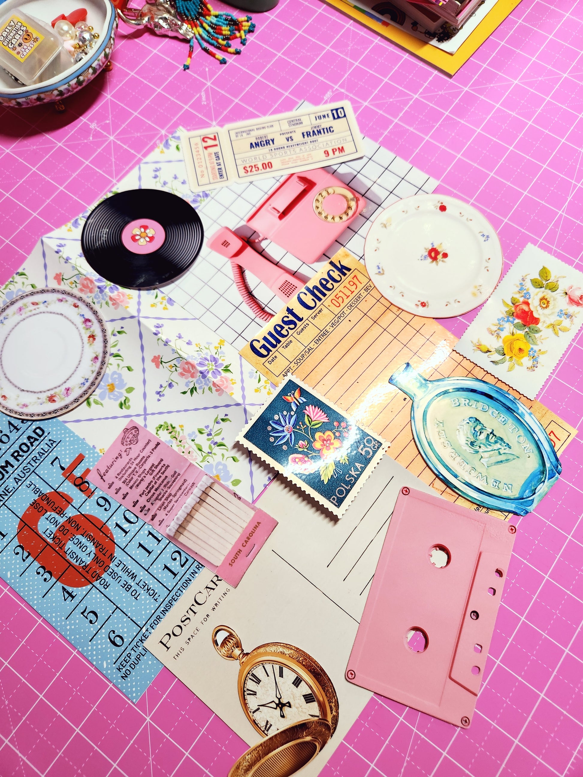 Collection of vintage items including a cassette tape, records, and matchbooks on a pink surface.