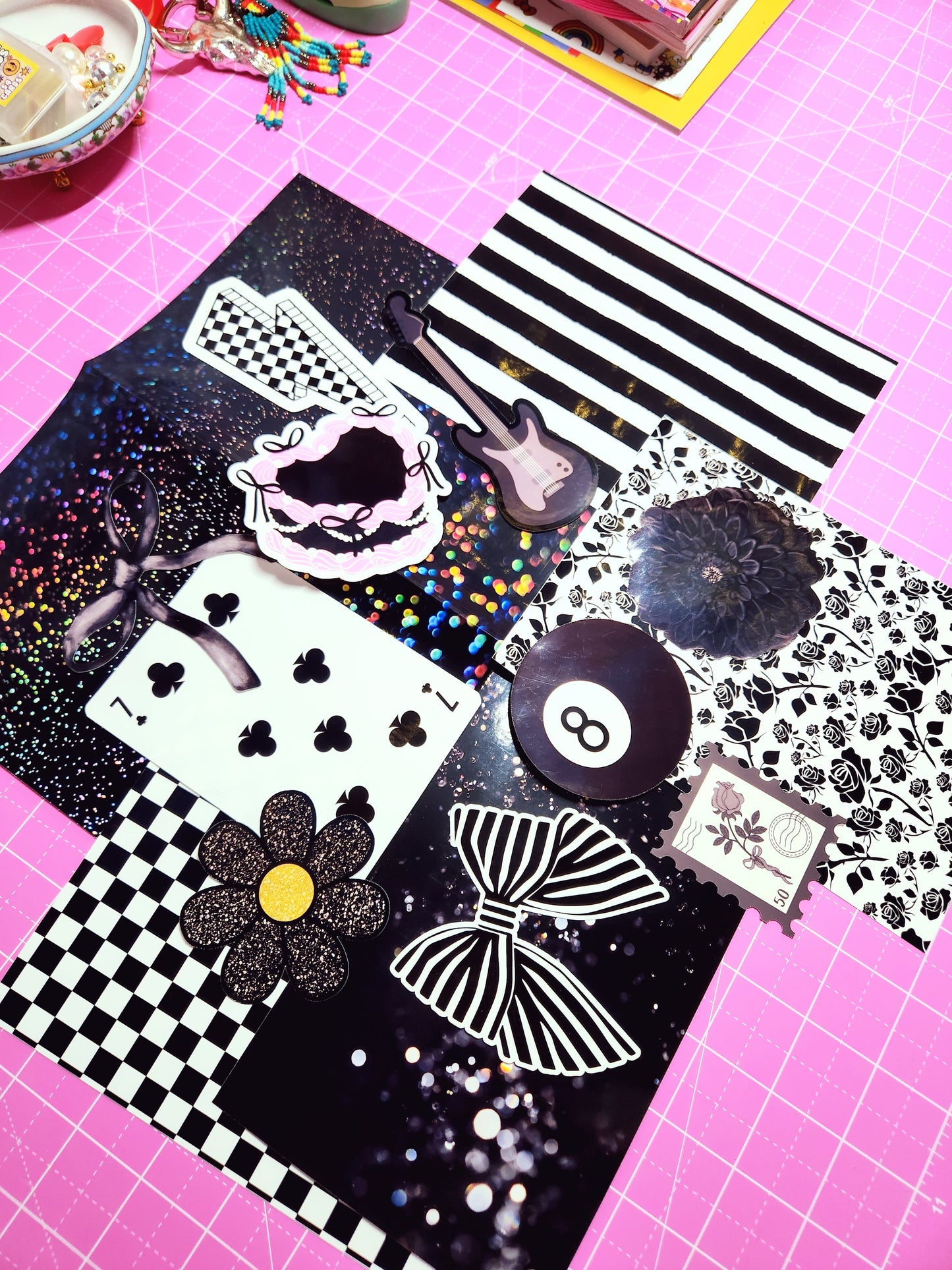 Collage of decorative items including a bow, flower, and abstract designs on a pink grid background.