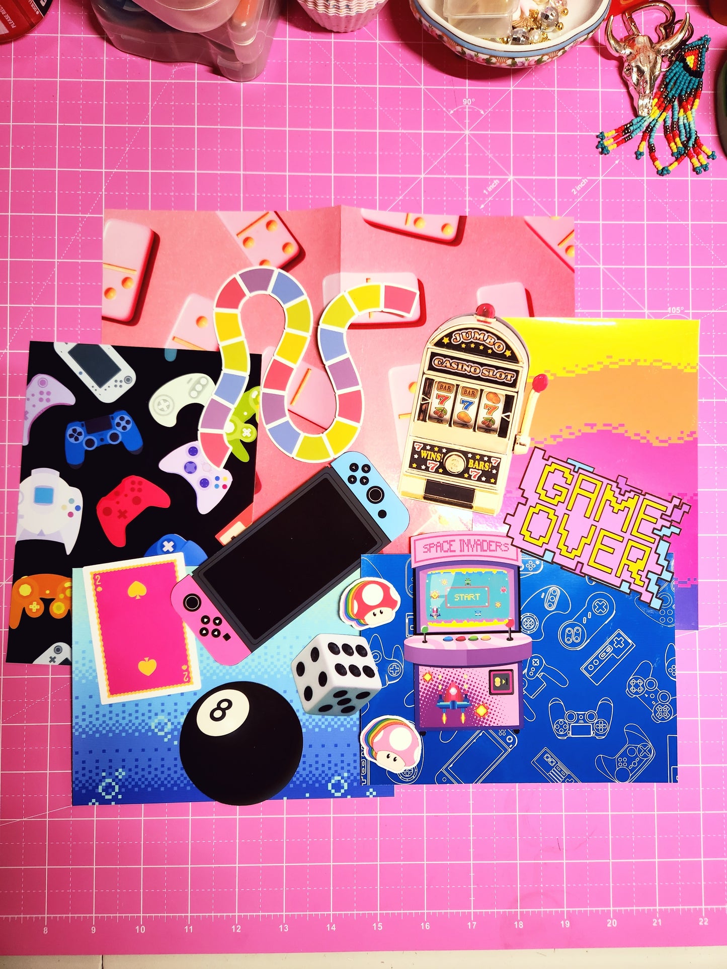 Colorful game-themed phone case on a pink cutting mat with gaming elements.