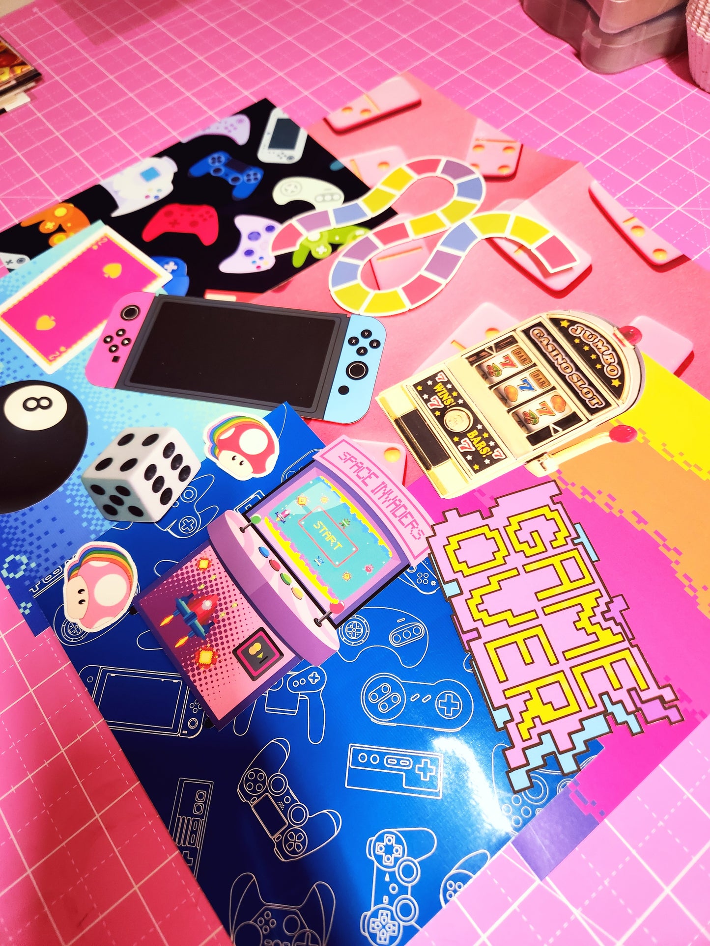 Colorful gaming-themed items on a pink and blue checkered background with 'Game Over' text.