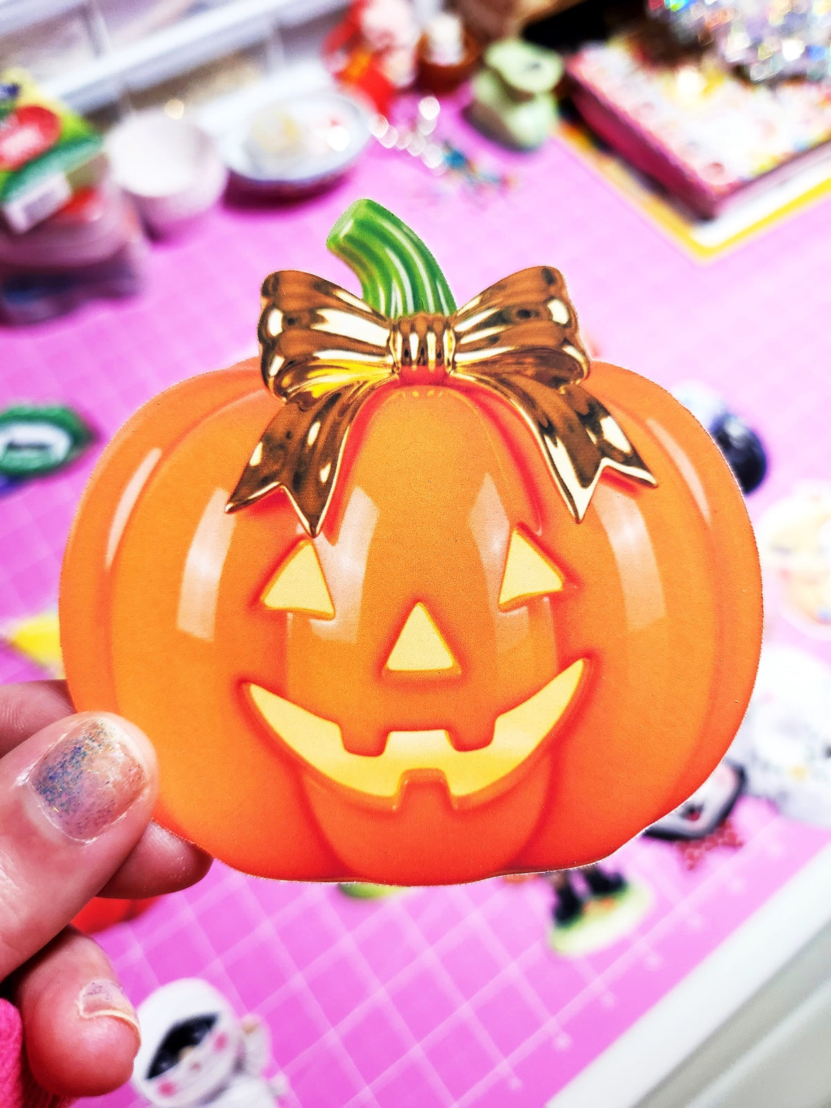 Decorative pumpkin with a gold bow held by a hand on a colorful background