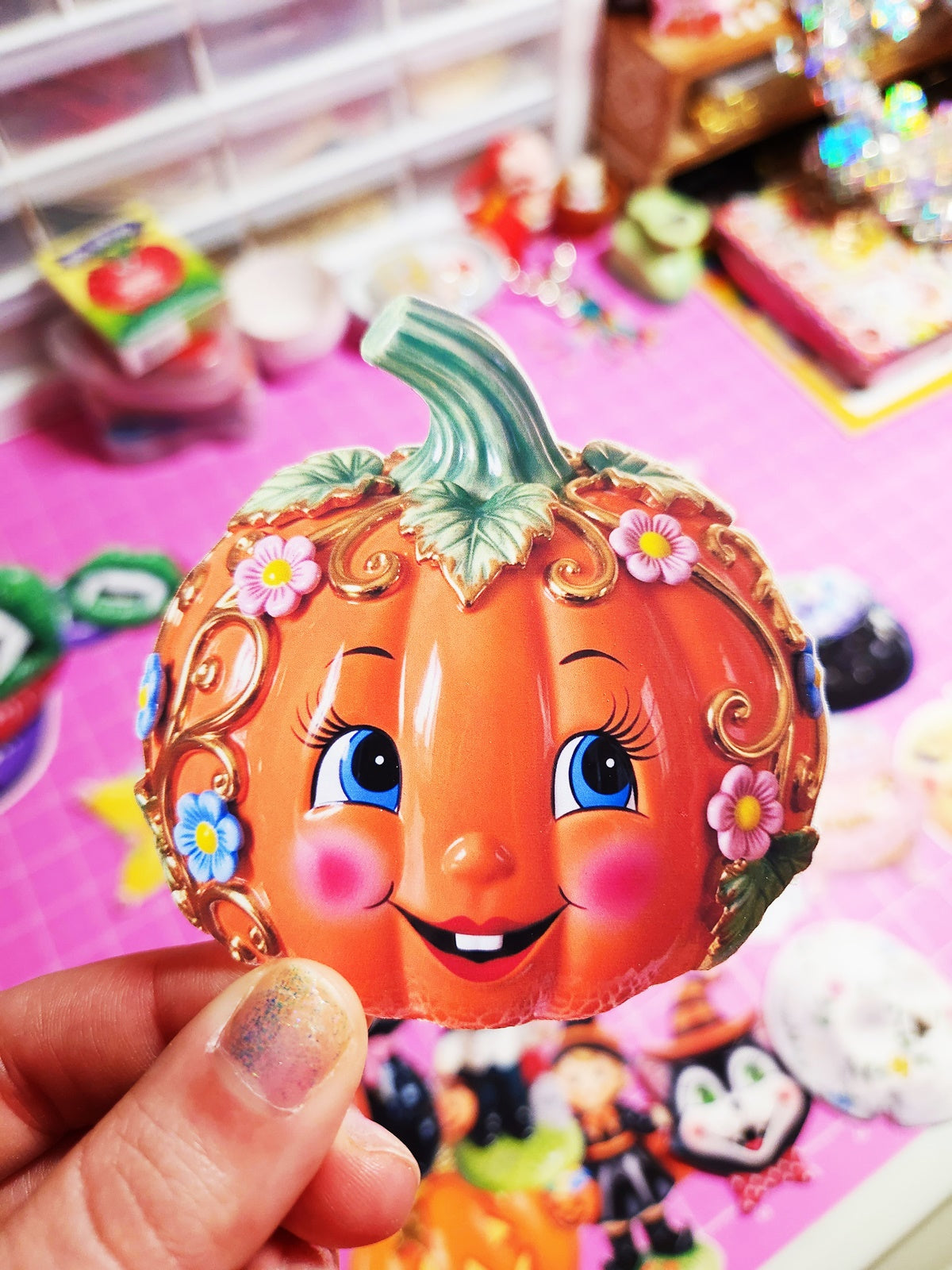 Decorative pumpkin with a face held by a hand against a colorful background