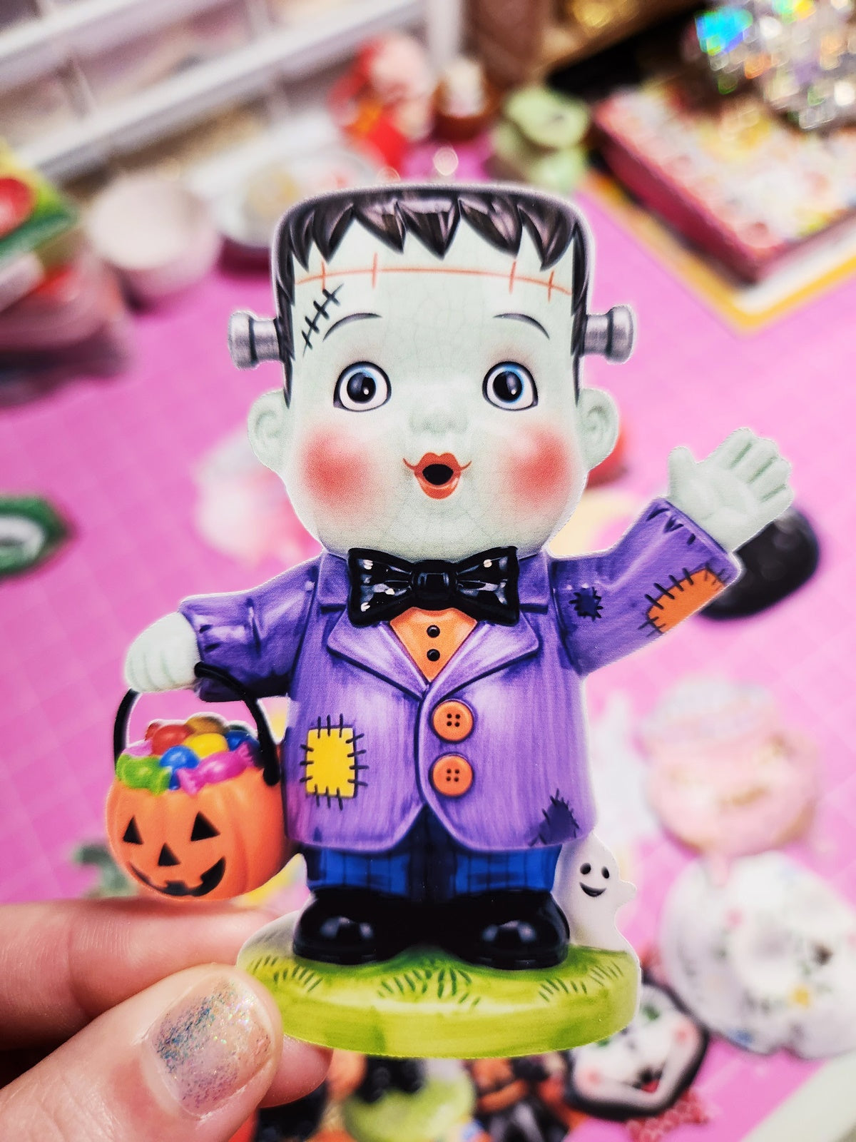 Halloween-themed figurine of a character in a purple suit with candy bucket on a pink background