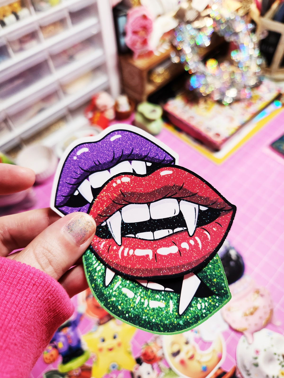 Sticker of vampire lips held by a hand with a colorful background
