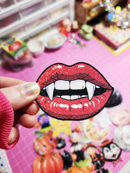 Lip patch with vampire design held by a hand against a colorful, blurred background