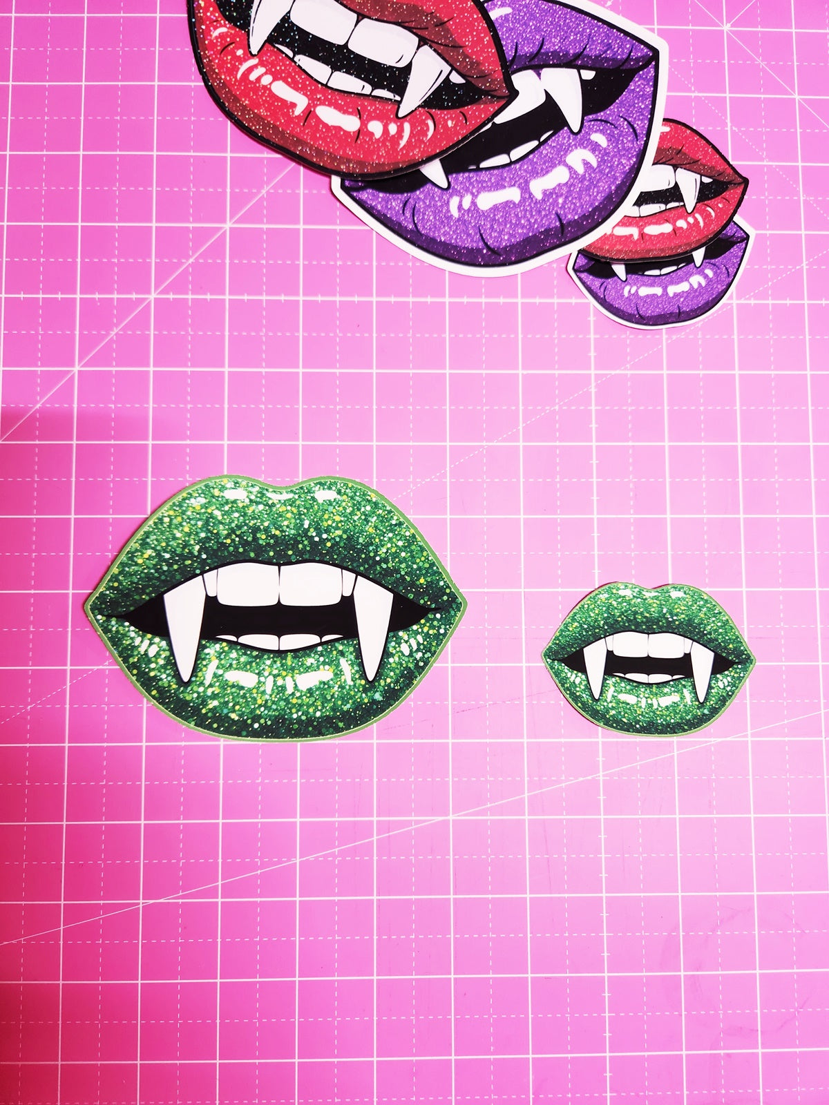 Colorful lips with fangs on a pink grid background