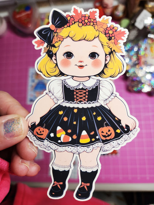 Sticker of a girl in a Halloween-themed outfit held against a pink background