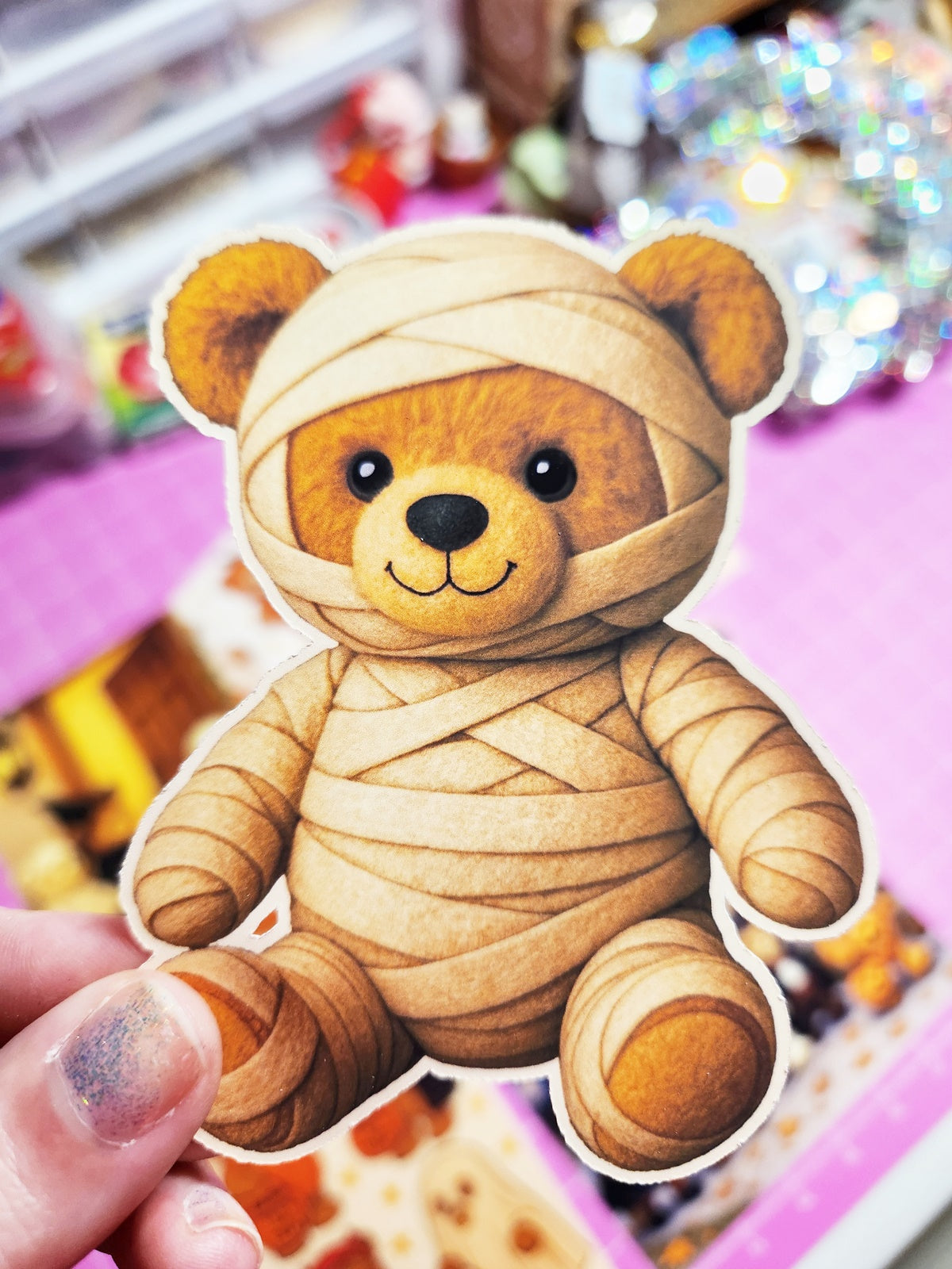 Teddy bear wrapped in bandages held by a hand with a colorful background