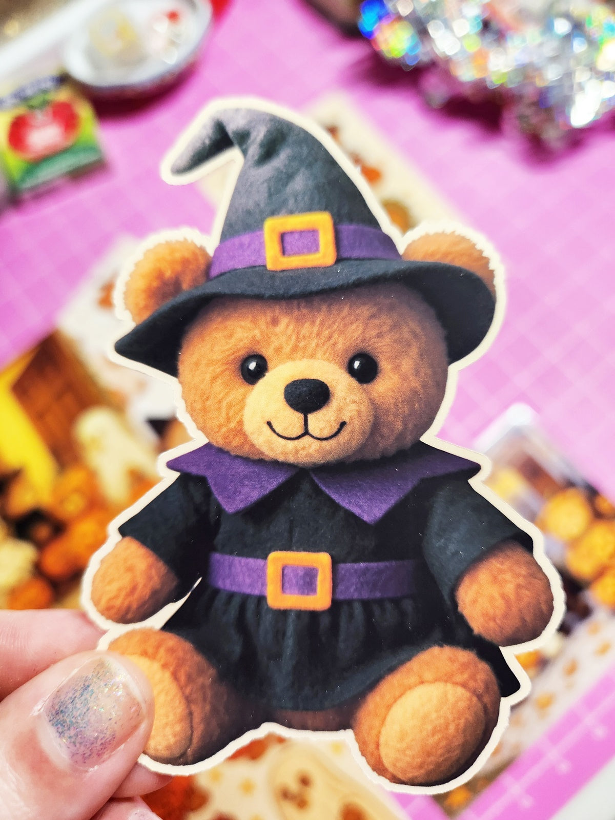 Teddy bear dressed as a witch held by a hand with a blurred background