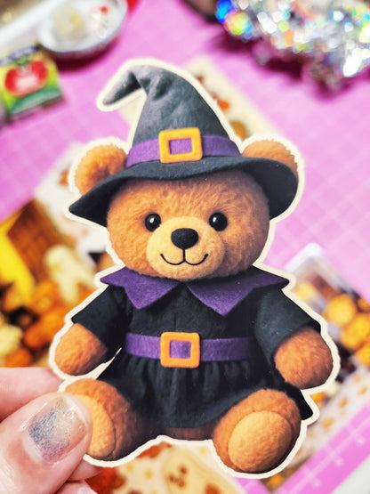 Teddy bear dressed as a witch held by a hand with a blurred background