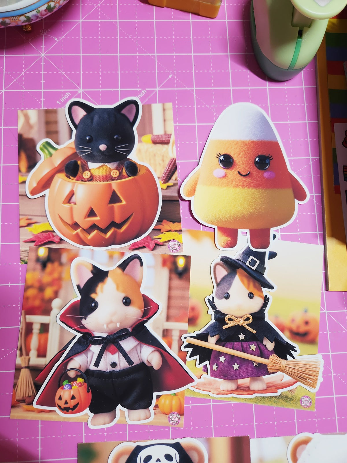 Set of Halloween-themed stickers featuring a black cat, candy corn, and other characters on a pink grid background.