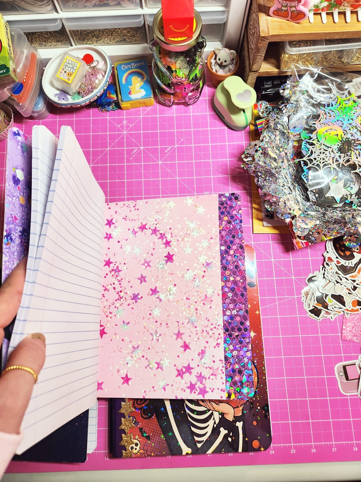 Crafting materials on a pink cutting mat with various decorative items.