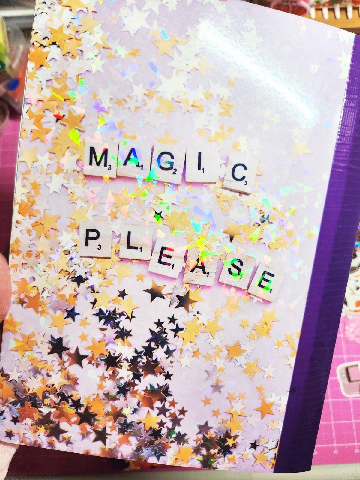 Decorative notebook with star patterns and colorful letter tiles spelling 'MAGIC PLEASE'.